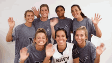 a group of women wearing navy shirts waving