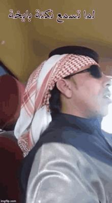 a man wearing a head scarf and sunglasses is sitting in a car
