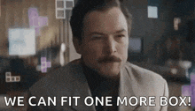 a man with a mustache is saying `` we can fit one more box '' while wearing a suit .