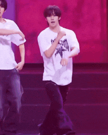 a man in a white t-shirt that says ' 100 % ' on it is dancing on a stage