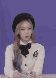 a girl wearing a black hat and a white sweater with a bow tie