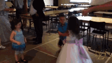 a little girl in a purple dress is dancing with a boy