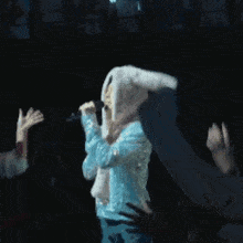 a person wearing bunny ears is singing into a microphone on a stage