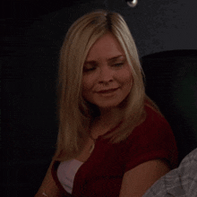 a blonde woman wearing a red shirt is smiling for the camera