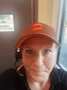 a woman wearing a mcdonald 's hat and headset smiles for the camera