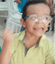 a young boy wearing glasses and a yellow shirt looks at the camera
