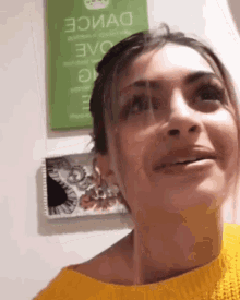 a woman wearing a yellow sweater is smiling in front of a green sign that says evo