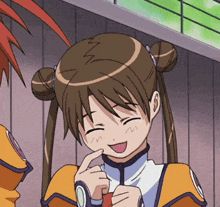 a girl with brown hair is smiling and holding her finger to her mouth