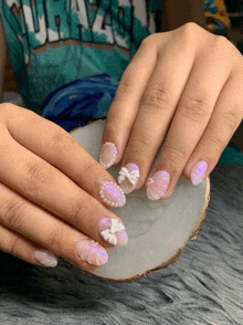 a woman 's nails are decorated with bows and pearls and she is wearing a shirt that says hawaii