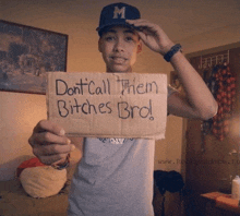 a young man holds up a cardboard sign that says " don t call them bitches bro "