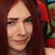 a close up of a woman 's face with red hair and blue eyes sitting in a chair .