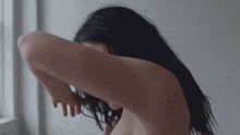 a woman without a shirt is covering her face with her arm