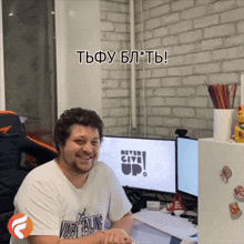 a man sitting at a desk with a computer monitor that says never give up