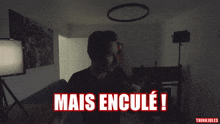 a man in a dark room with the words mais encule written on the bottom