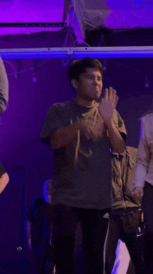 a man wearing a t-shirt with the letters x on it is clapping his hands