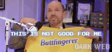 a man is holding up a yellow shirt that says buttfingerer dark web