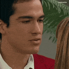 a man and a woman are looking at each other and the man is wearing a red jacket .
