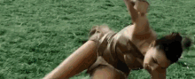 a woman in a bikini is laying on her stomach in a field .