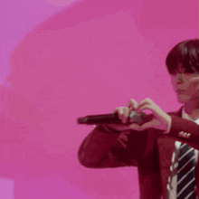 a man in a red suit and tie is making a heart shape with his hands while singing into a microphone