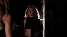 a woman is standing in front of a mirror in a dark room and looking at herself .