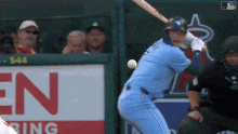 a baseball player swings his bat at a ball in front of a sign that says en