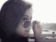 a close up of a woman wearing sunglasses looking out a window