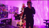 a man wearing headphones is standing in front of a christmas tree .