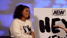 a woman sits in front of a sign that says hey