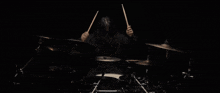 a man in a black shirt is playing drums in a dark room .