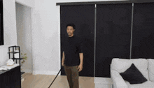 a man is standing in a living room with a vacuum cleaner and a couch .