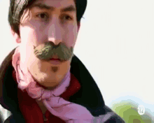 a man with a mustache and a pink scarf around his neck has the number 12 on his collar