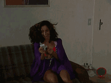 a woman in a purple robe is sitting on a couch holding a card in her hand