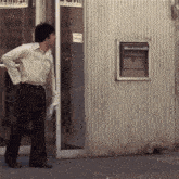 a man in a white shirt stands in front of a building with a sign on the side that says ' a '