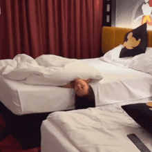 a woman laying on a bed with a mickey mouse pillow on the headboard