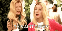 two blonde women are standing next to each other and talking .