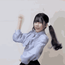 a woman in a blue shirt and black skirt is dancing with her hands in the air .