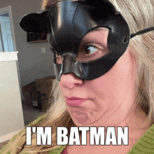 a woman wearing a cat mask with the words i 'm batman on her face