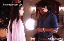 a man and a woman are standing next to each other in a room and talking to each other .