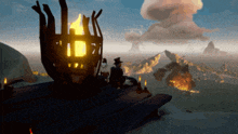 a man sits in front of a torch on a wooden deck overlooking the ocean