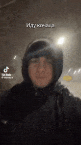 a man wearing a hooded jacket is taking a selfie with a tiktok account