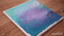 a blue and purple painting on a wooden table made by chloe art