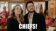 a man and woman are standing next to each other and the man is saying chiefs !