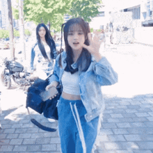 a girl in a white tank top and blue pants waves