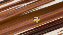 a yellow and blue volleyball is flying through the air on a brown background .