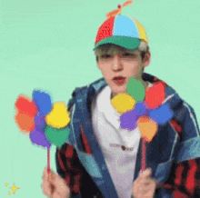 a man wearing a colorful hat is holding two colorful pinwheels .