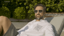 a man wearing sunglasses and a white shirt is laying in a chair with brazilponcho written on the bottom left