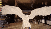 a screenshot of a video game shows a person with angel wings standing in front of a christmas tree
