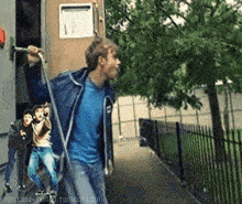 a man in a blue shirt is holding a rope in front of a building