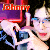 a person wearing glasses making a heart shape with their hands and the name johnny written above them