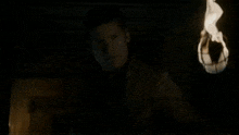 a person is holding a torch with flames coming out of it in the dark .